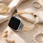 Natural stone Apple Watch band styled with pearls and silver jewelry on warm travertine