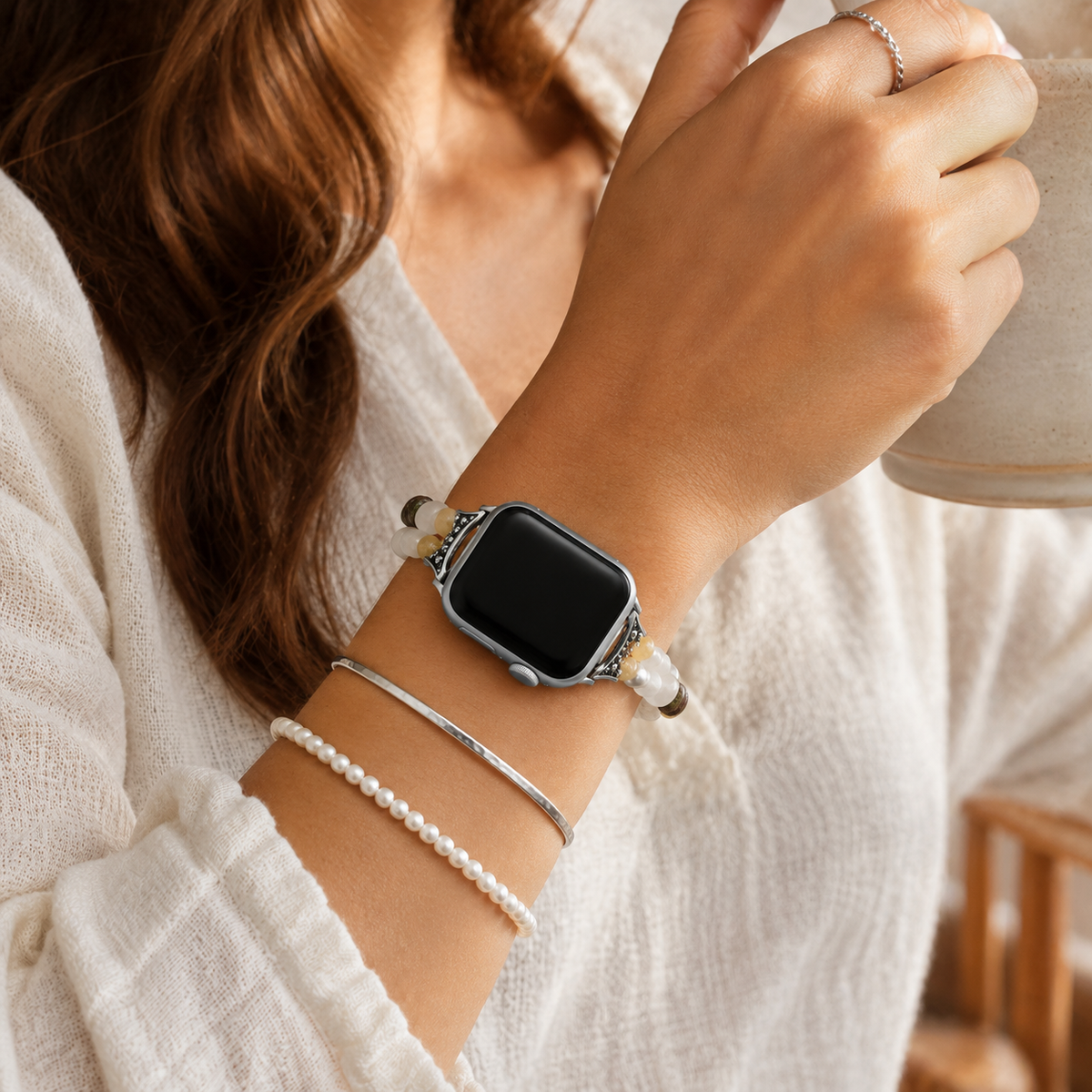 Woman wearing a natural stone beaded Apple Watch band with layered silver and pearl bracelets